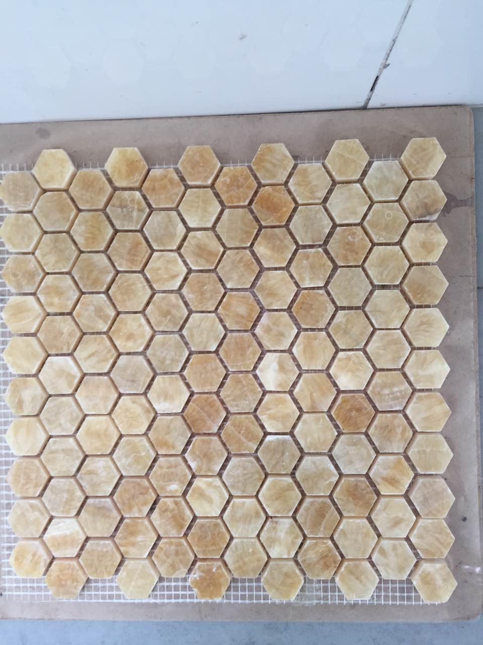 Real product photo — complete mesh-mounted sheet of the golden beige hexagon natural marble mosaic; natural stone variation and approved sample control final appearance