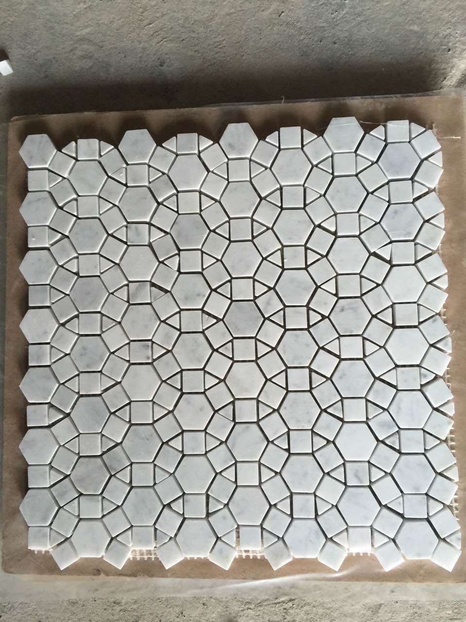 Real product photo — complete mesh-mounted sheet of the white interlocking rosette natural marble mosaic; natural stone variation and approved sample control final appearance